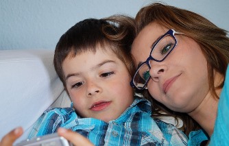 woman and boy on couch looking at device out of view